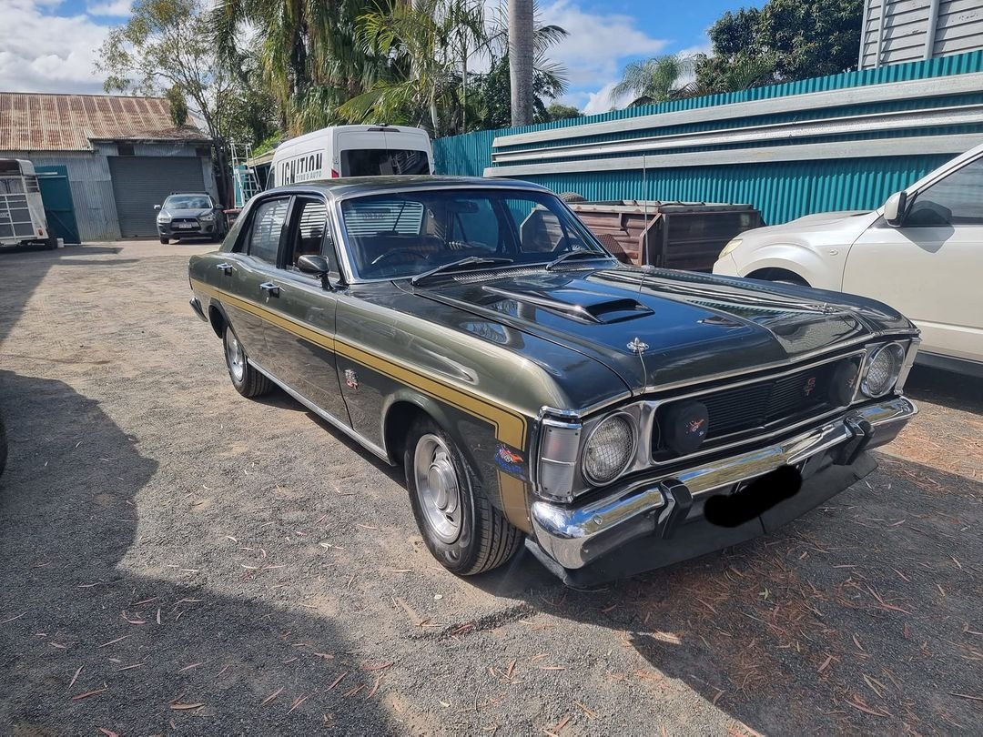 A green and gold Ford Falcon GT parked in the yard beside the Ignition Tyre and Auto service van